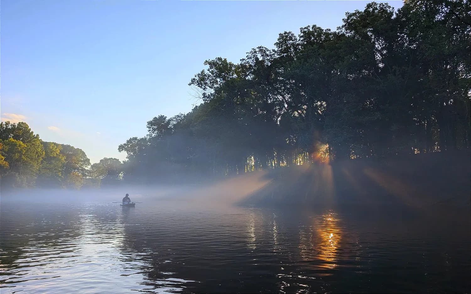 Sun rays through mist over the river at sunrise
